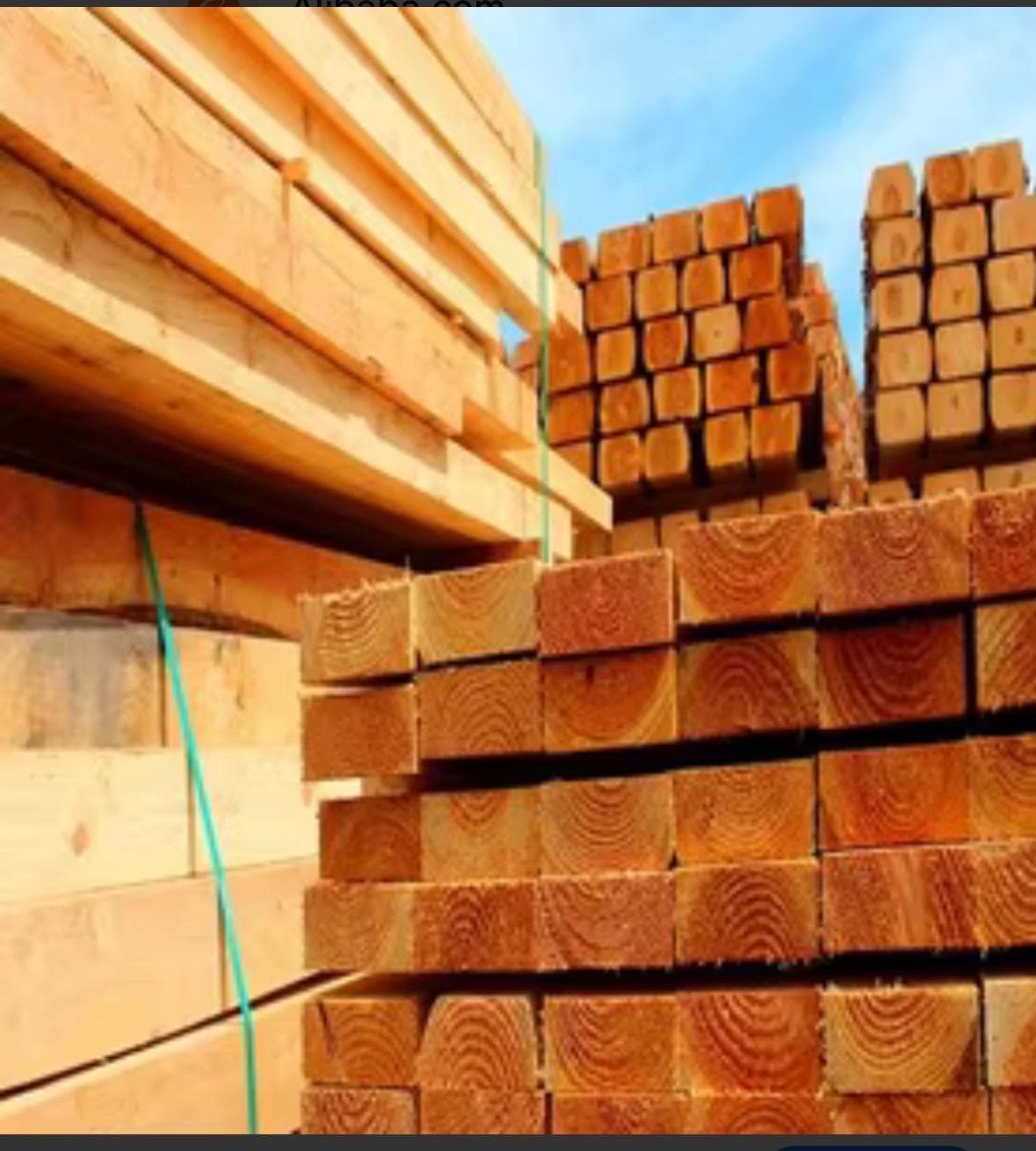 Warm-toned red wood planks stacked in an outdoor industrial lumber yard
